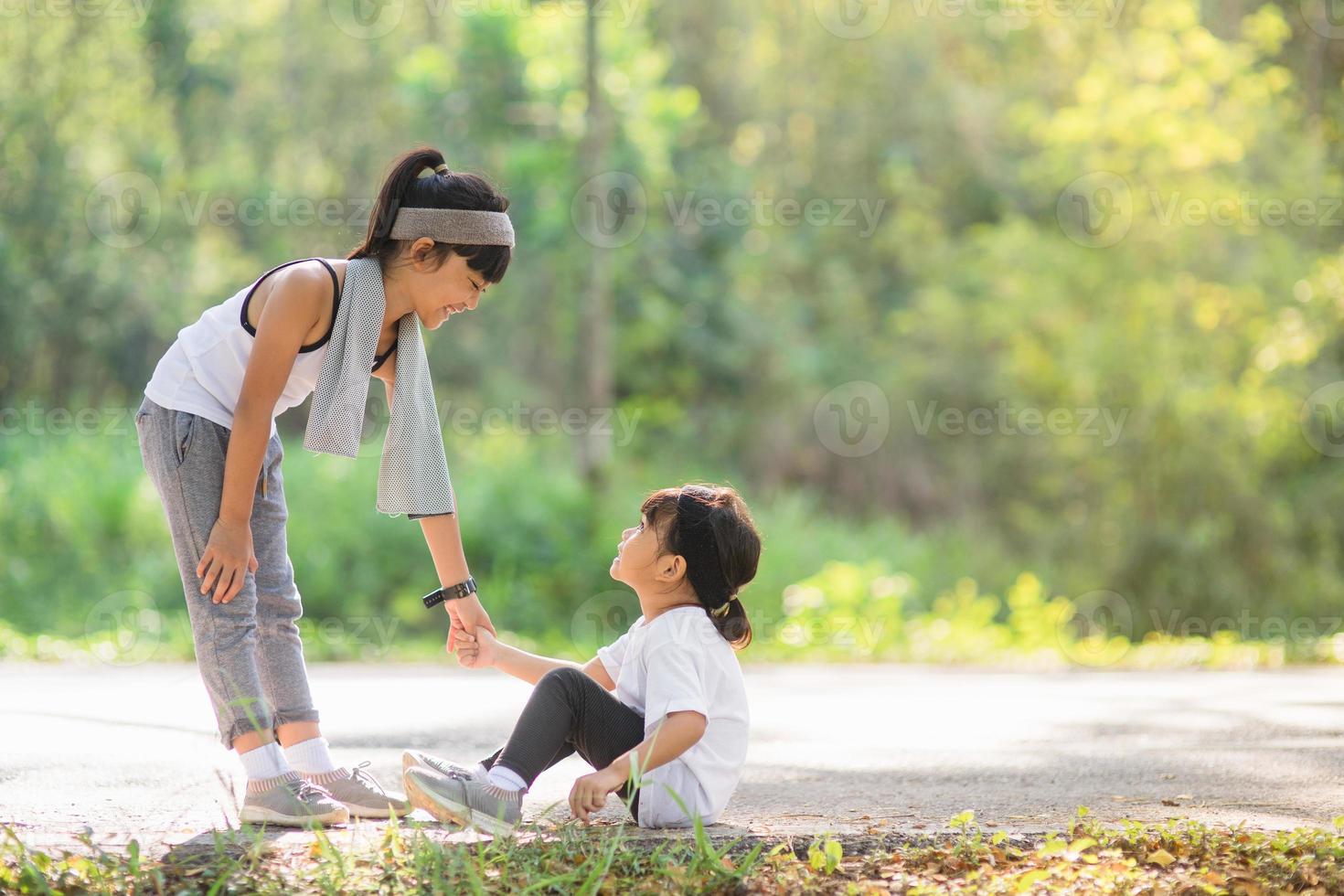 Cute asian girl give hand to help sister accident during running photo