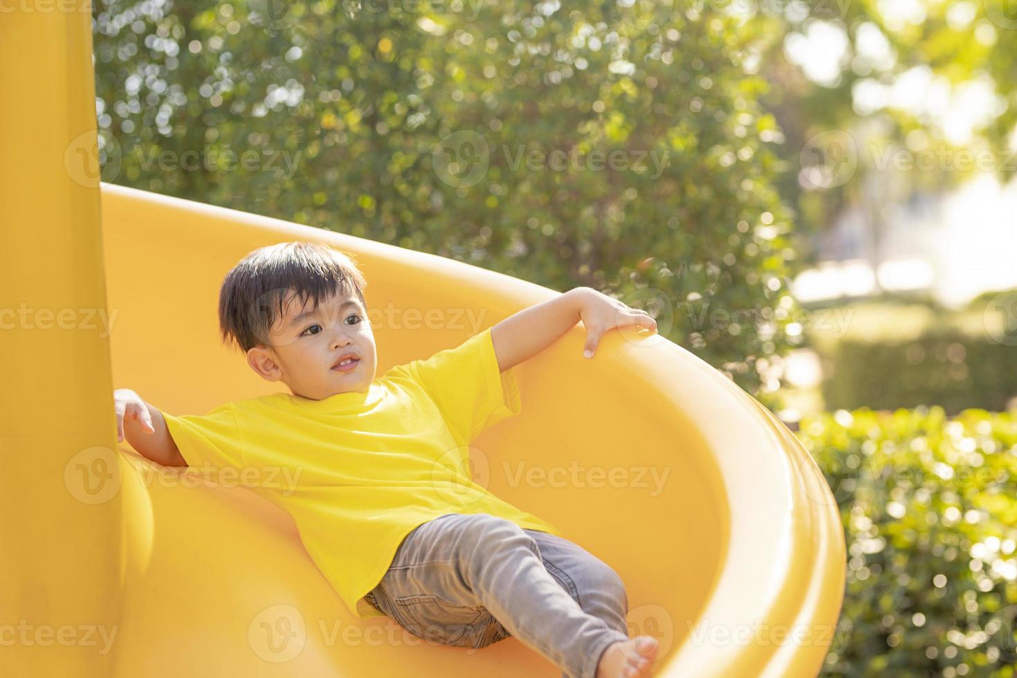 Child playing on the outdoor playground. Kids play in school or kindergarten yard. Active kid on colorful slide and swing. Healthy summer activity for children. photo