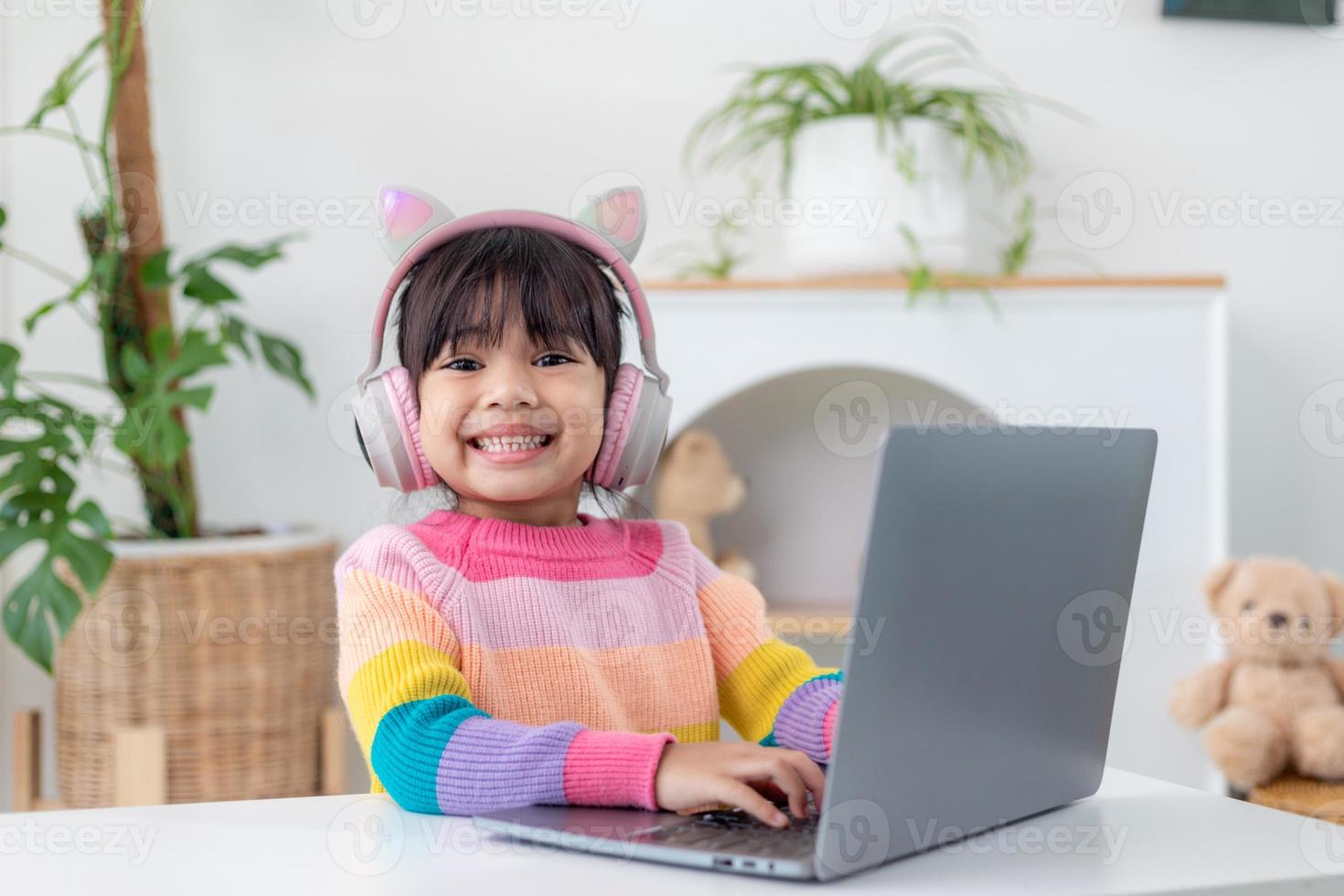 Smiling little Asian girl have a video call distant class with teacher using laptop, social distance during quarantine isolation during the Coronavirus photo