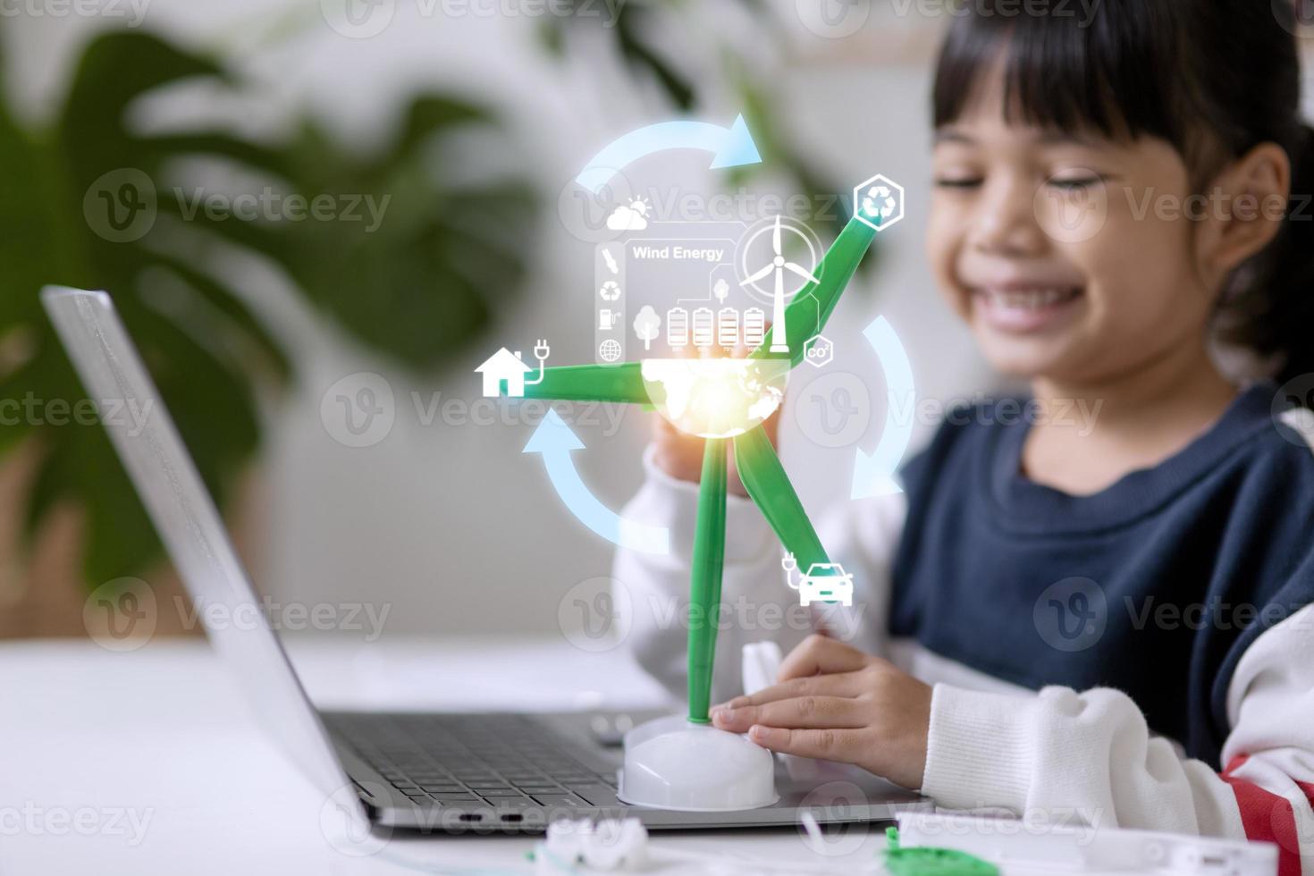 renewable energy, science, and technology concept - happy children with laptop computers, wind energy hologram,s and wind turbine models and icons. photo
