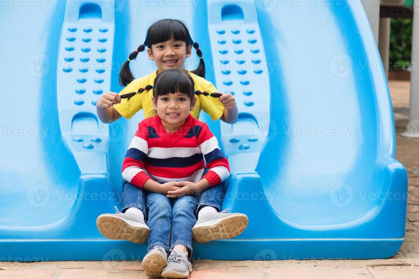 lindas niñas hermanos divirtiéndose en el patio de recreo al aire libre en un día soleado de verano foto