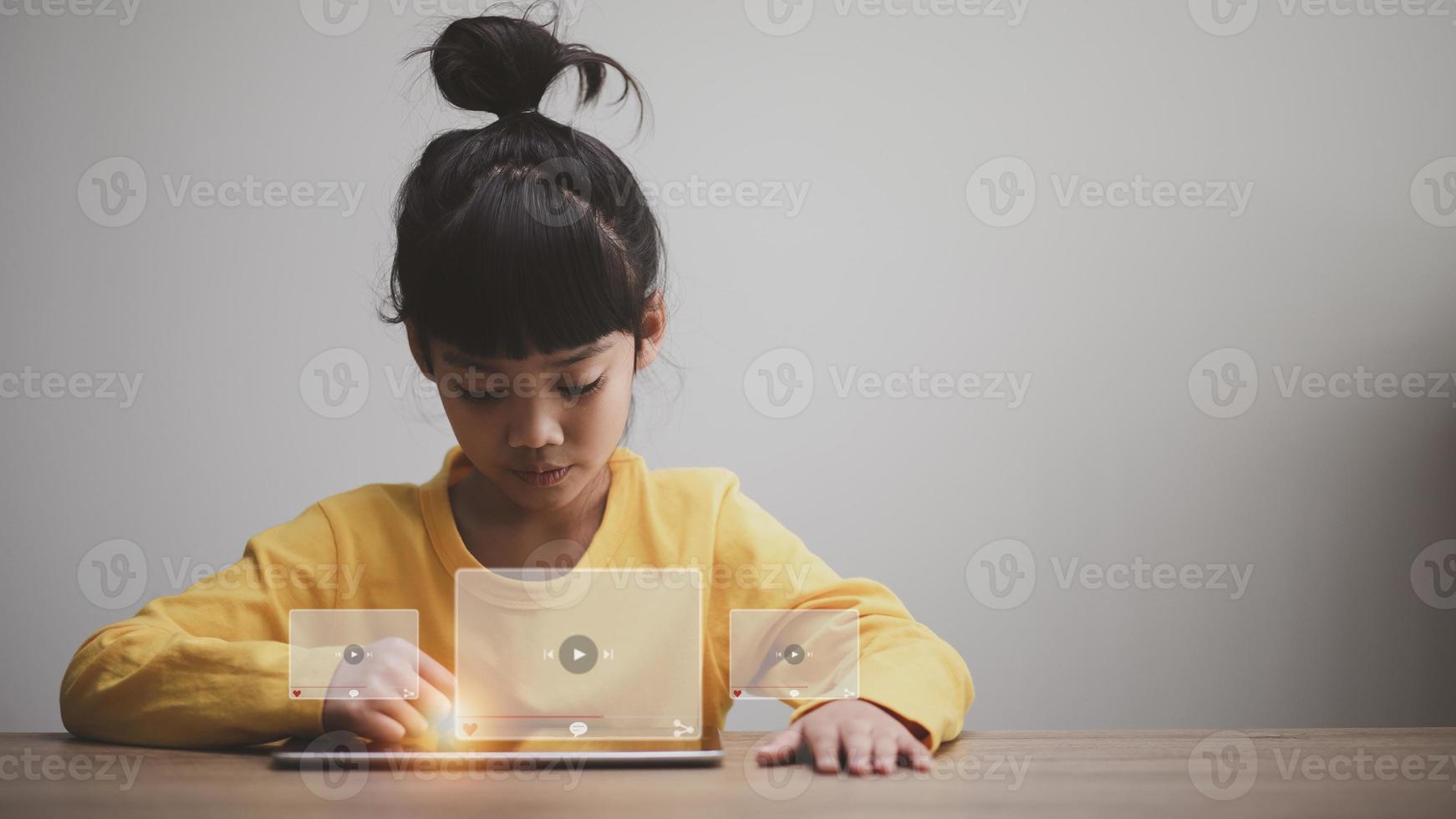 Asian girl using tablet for streaming online, watching video on internet, live study, tutorial, online learning, education, homeschooling. during Covid-19 pandemic lockdown. photo