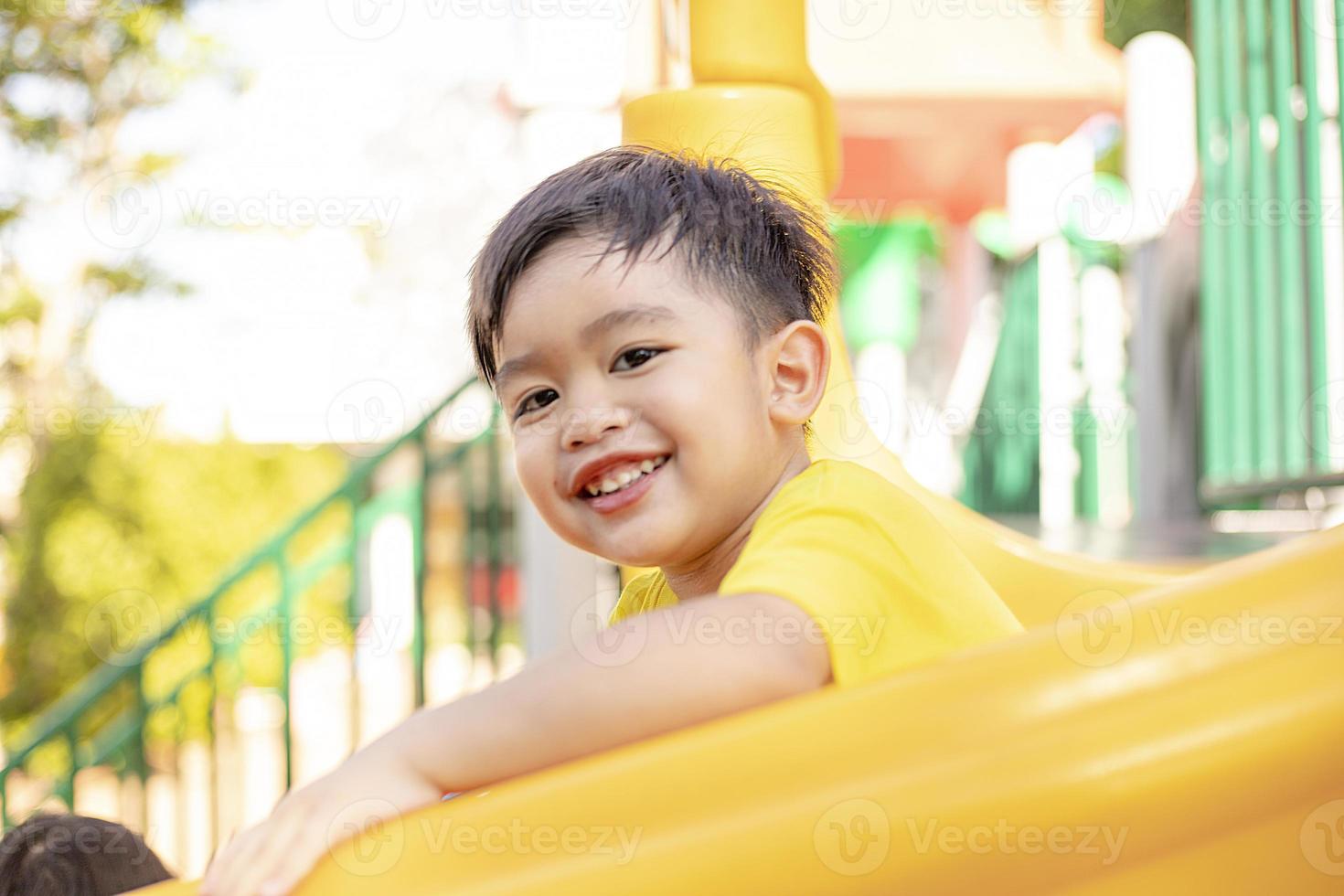 Child playing on the outdoor playground. Kids play in school or kindergarten yard. Active kid on colorful slide and swing. Healthy summer activity for children. photo
