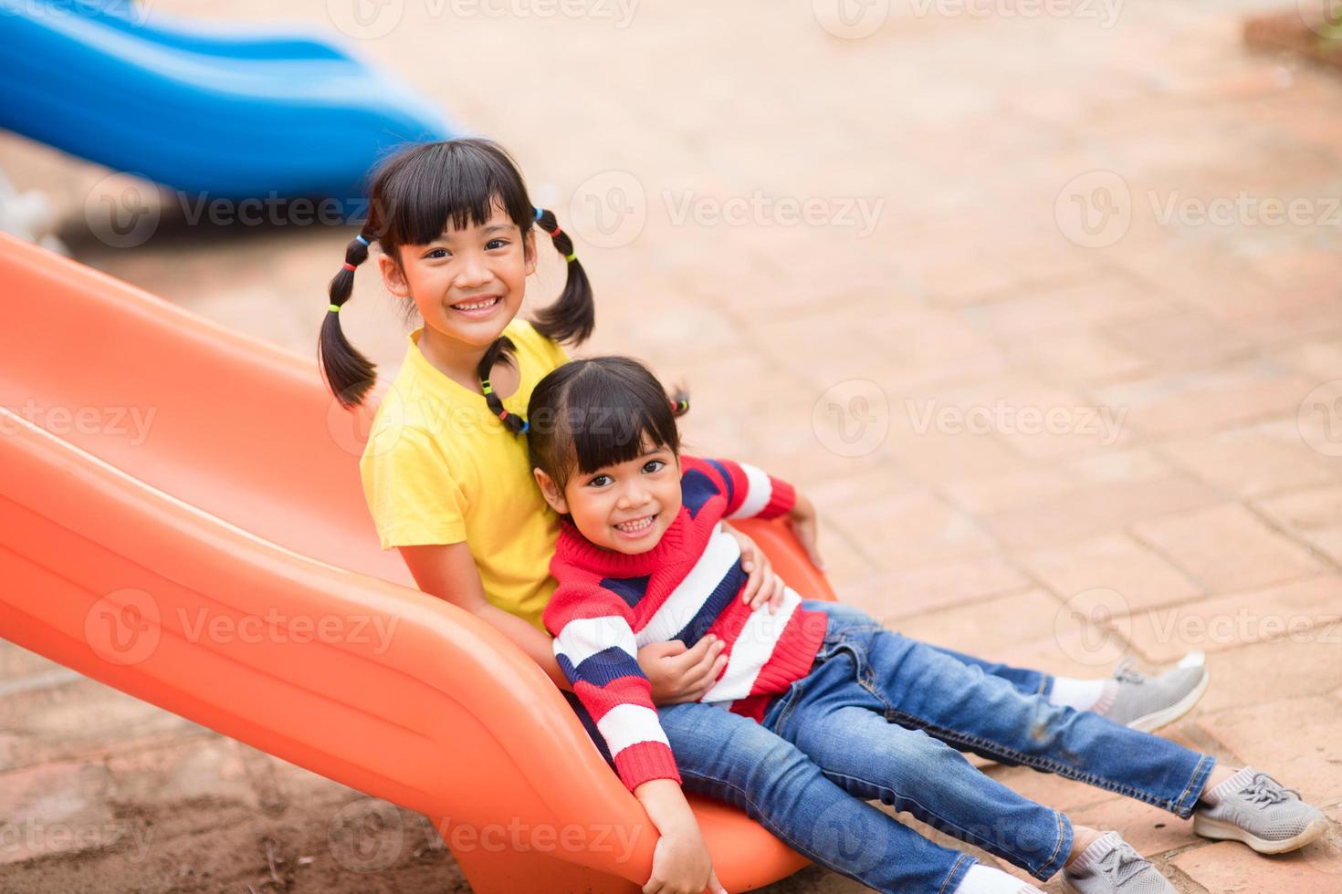 lindas niñas hermanos divirtiéndose en el patio de recreo al aire libre en un día soleado de verano. niños en tobogán de plástico. actividad divertida para niños. ocio deportivo activo para niños foto