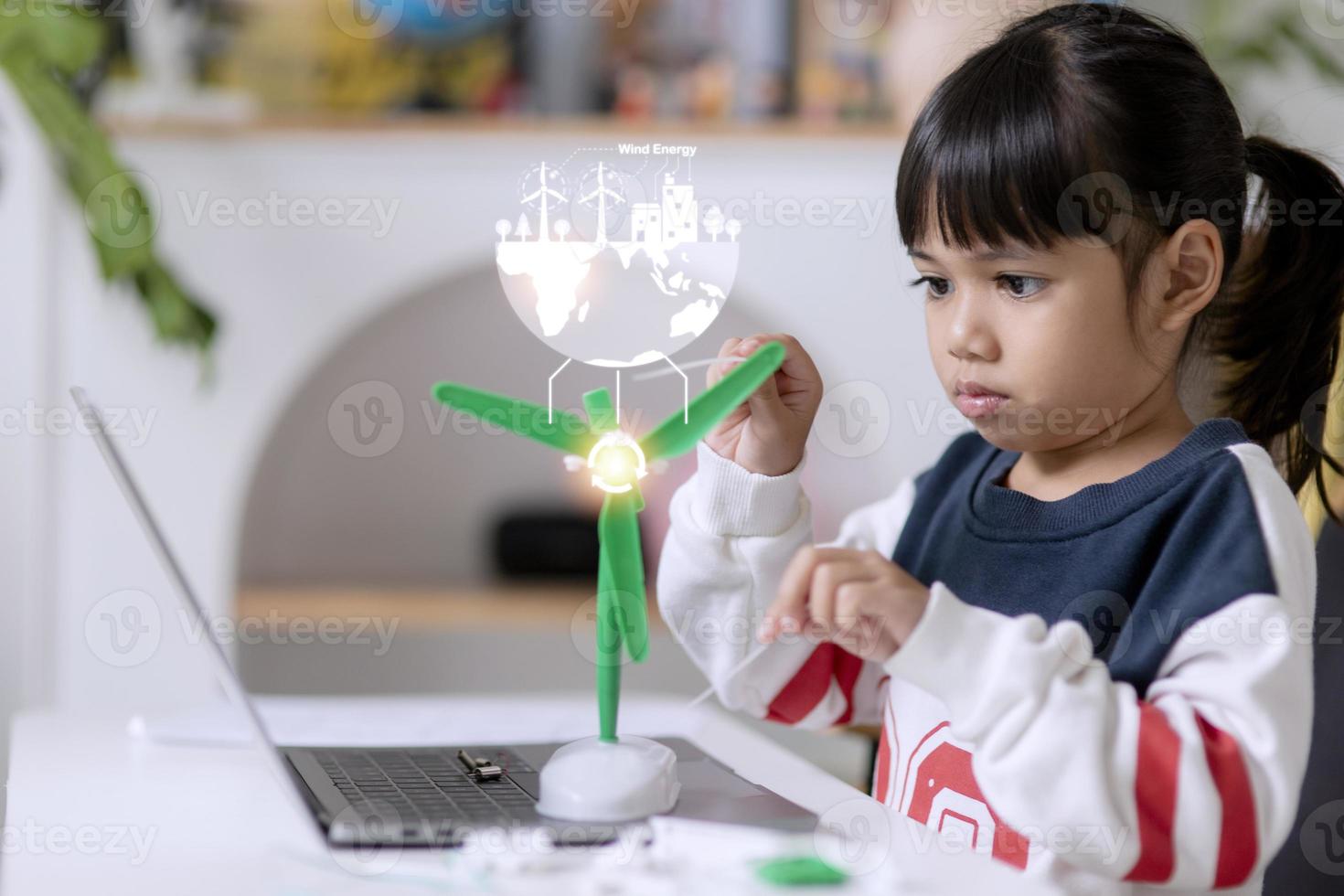 renewable energy, science, and technology concept - happy children with laptop computers, wind energy hologram,s and wind turbine models and icons. photo