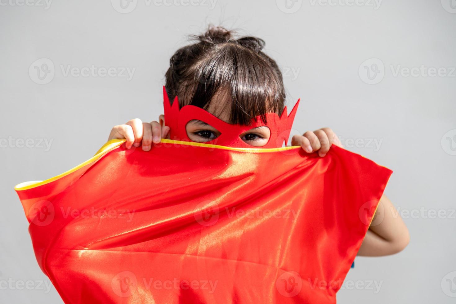 Little child girl plays superhero. Child on the white background. Girl power concept photo