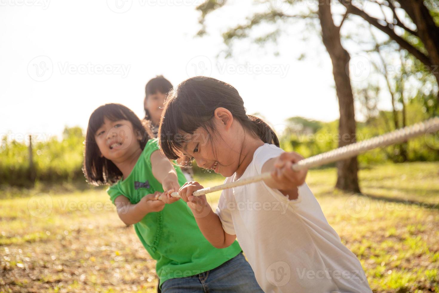 Children playing tug of war at the park on sunsut photo