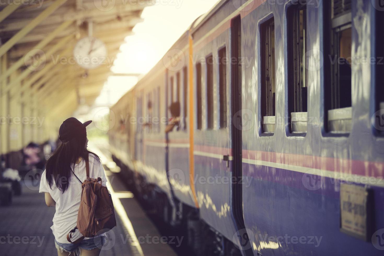 mujer viajera caminando y esperando el tren en la plataforma ferroviaria foto