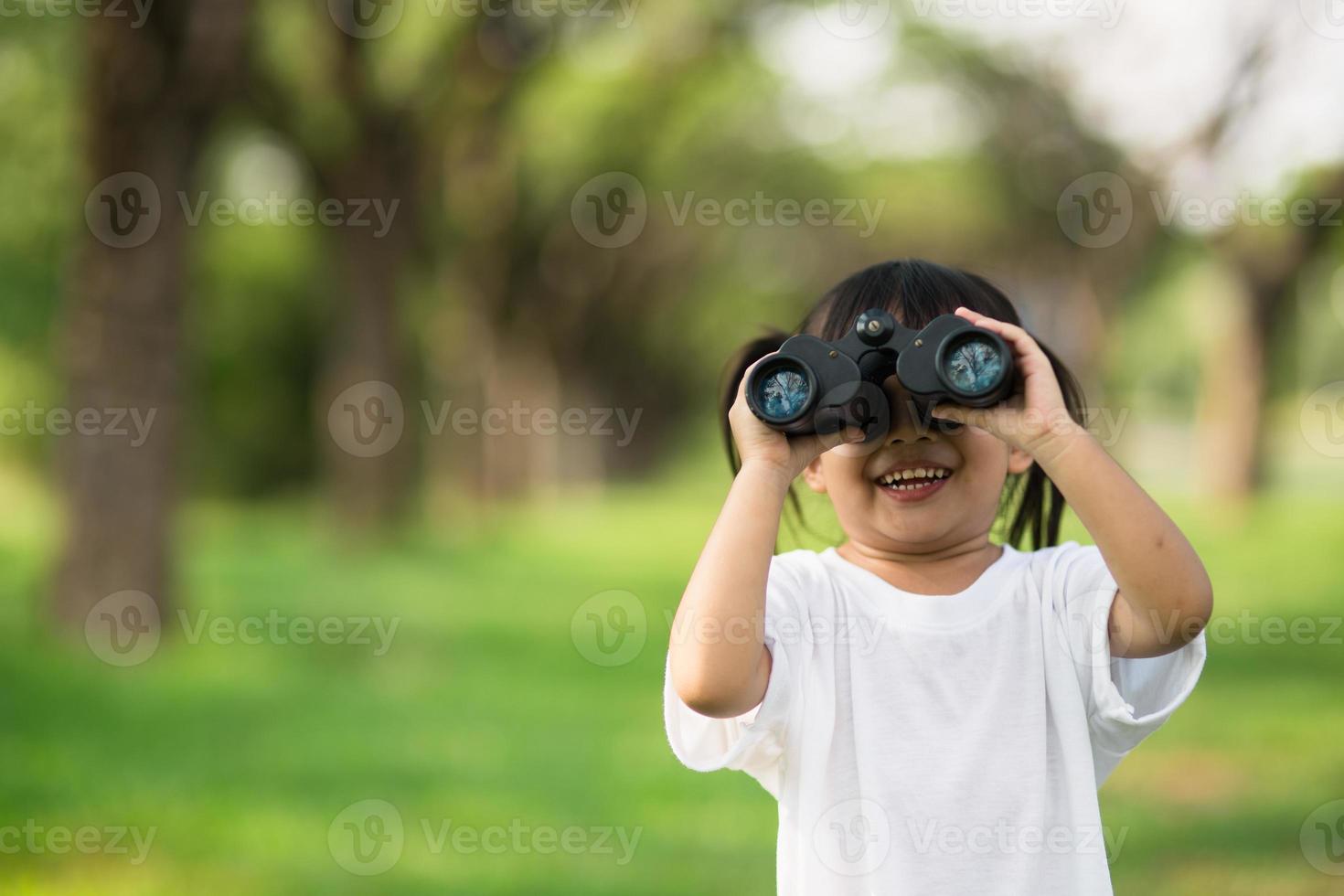 Happy child girl playing with binoculars. explore and adventure concept photo