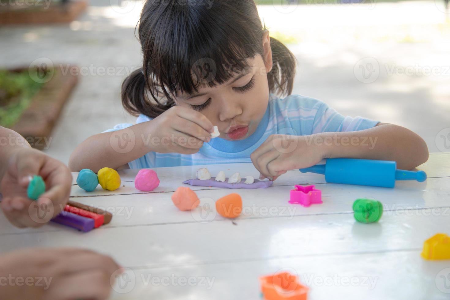 los niños asiáticos juegan con formas de moldeo de arcilla, aprendiendo a través del juego foto