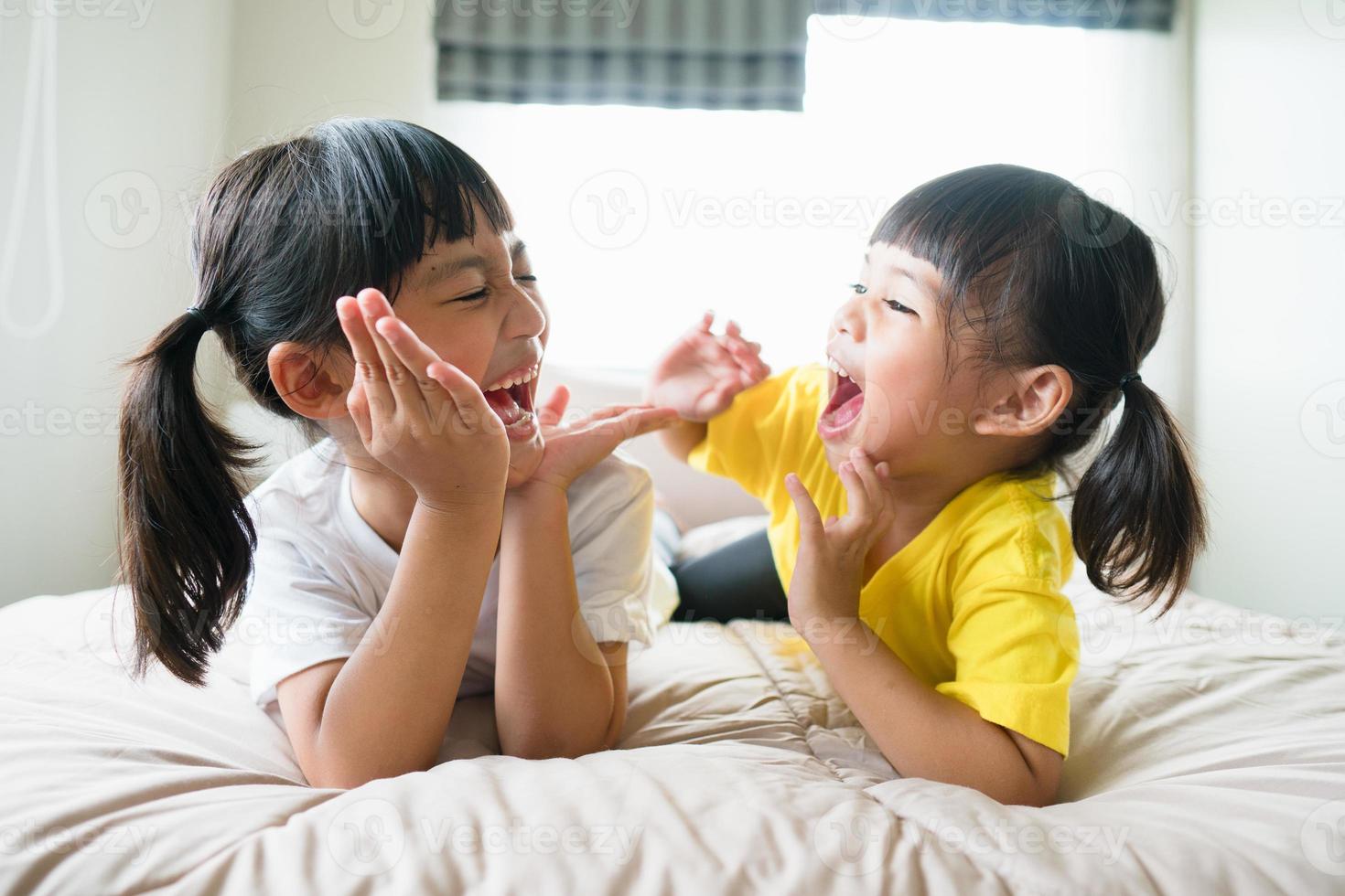 lindos niños asiáticos acostados en la cama foto