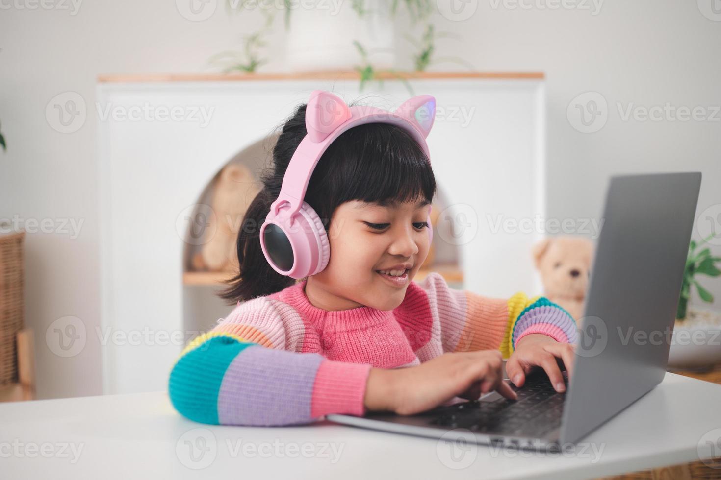 Smiling little Asian girl have a video call distant class with teacher using laptop, social distance during quarantine isolation during the Coronavirus photo