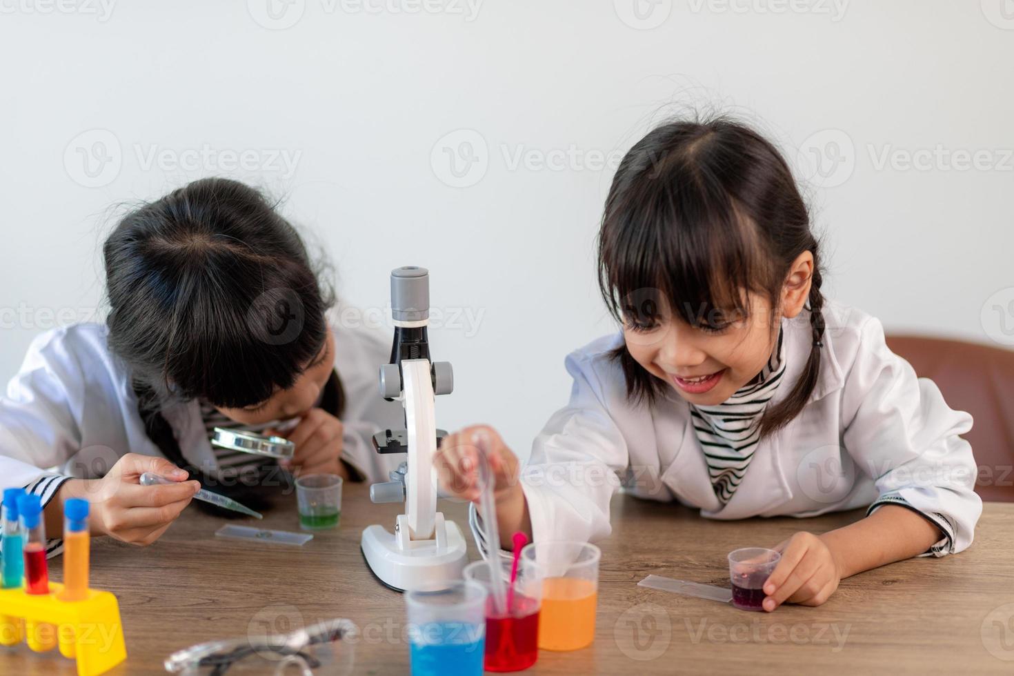 education, science, chemistry and children concept - kids or students with test tube making experiment at school laboratory photo