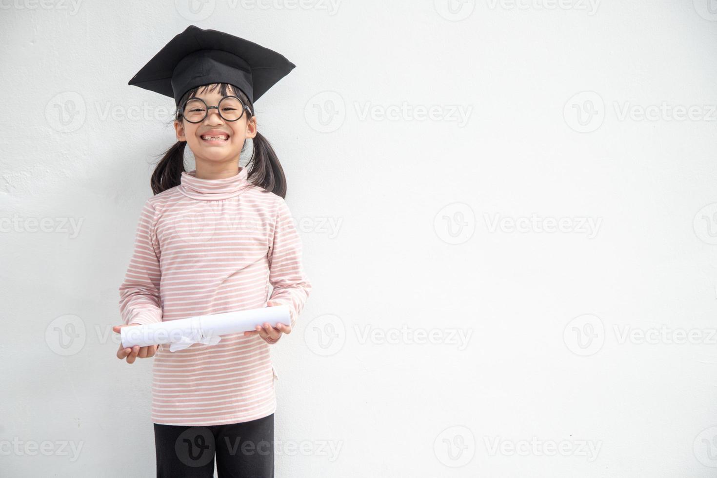 Happy Asian school kid graduate in graduation cap photo