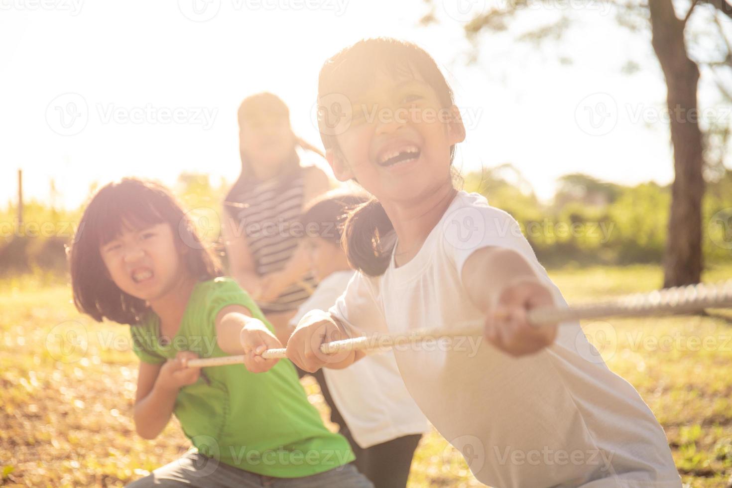 Children playing tug of war at the park on sunsut photo