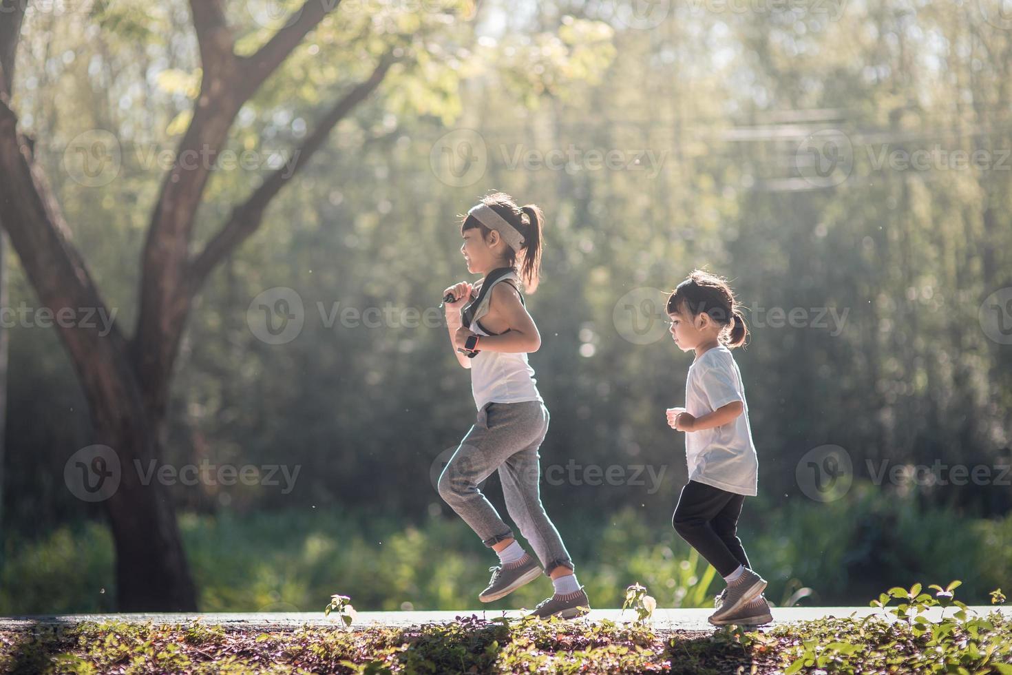 Two asian little girls having fun and running together in the park in vintage color tone photo