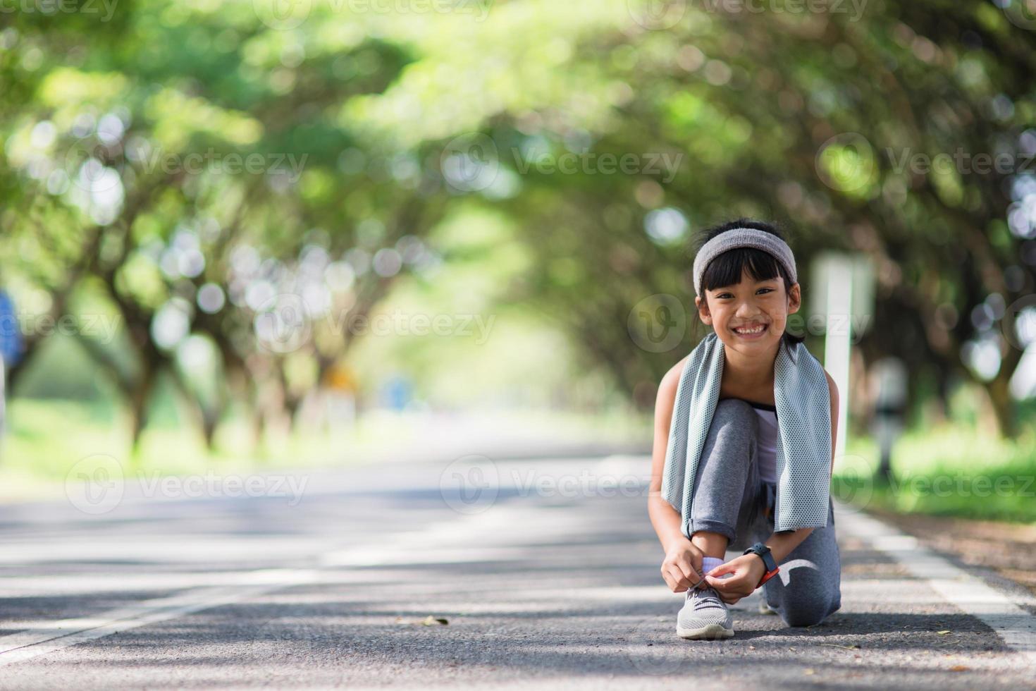 Kid tying running shoes. Happy Funny little asian girl fitness woman running at morning . Athletic young child running in the nature. Healthy lifestyle photo