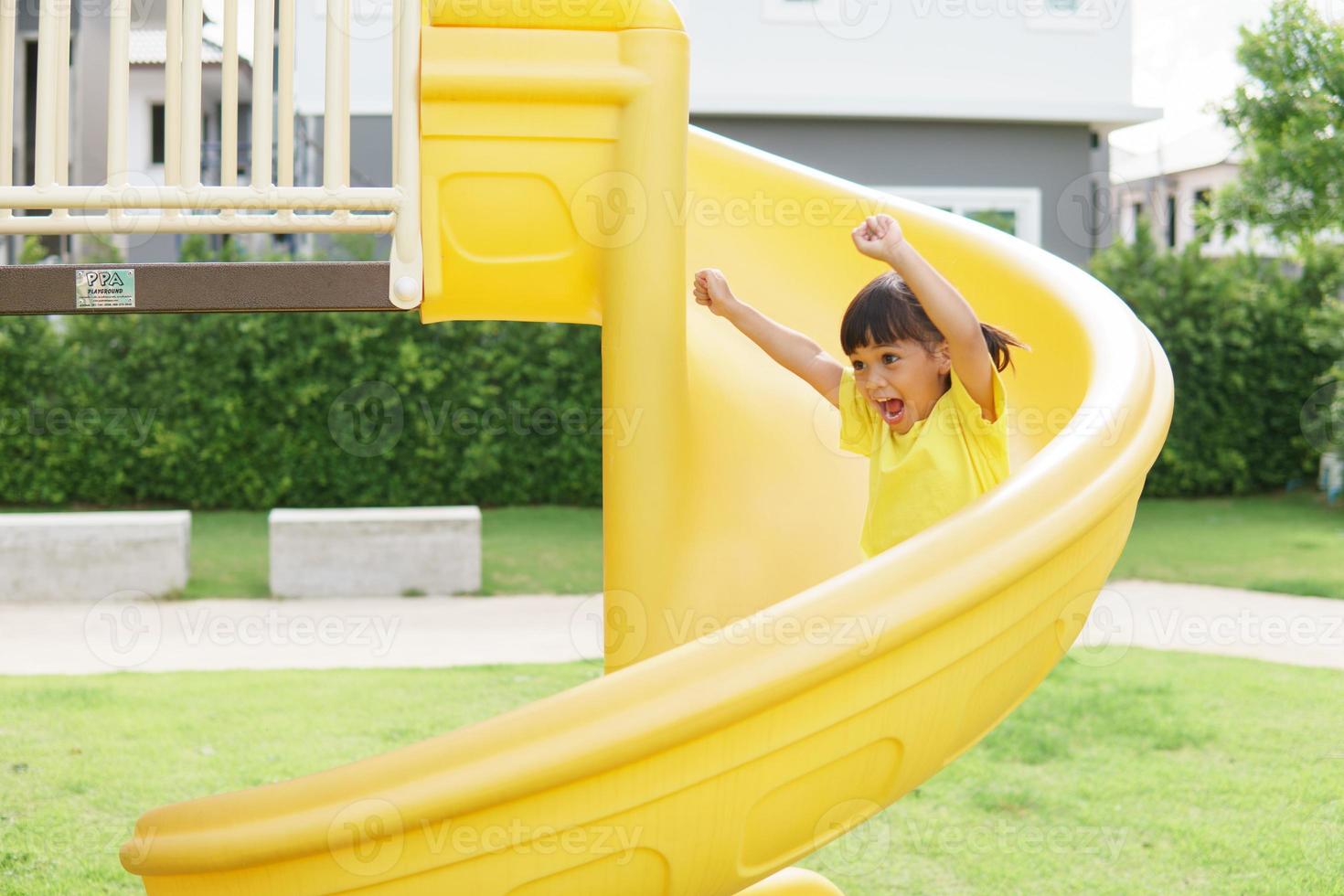 Child playing on outdoor playground. Kids play on school or kindergarten yard. Active kid on colorful slide and swing. Healthy summer activity for children. photo