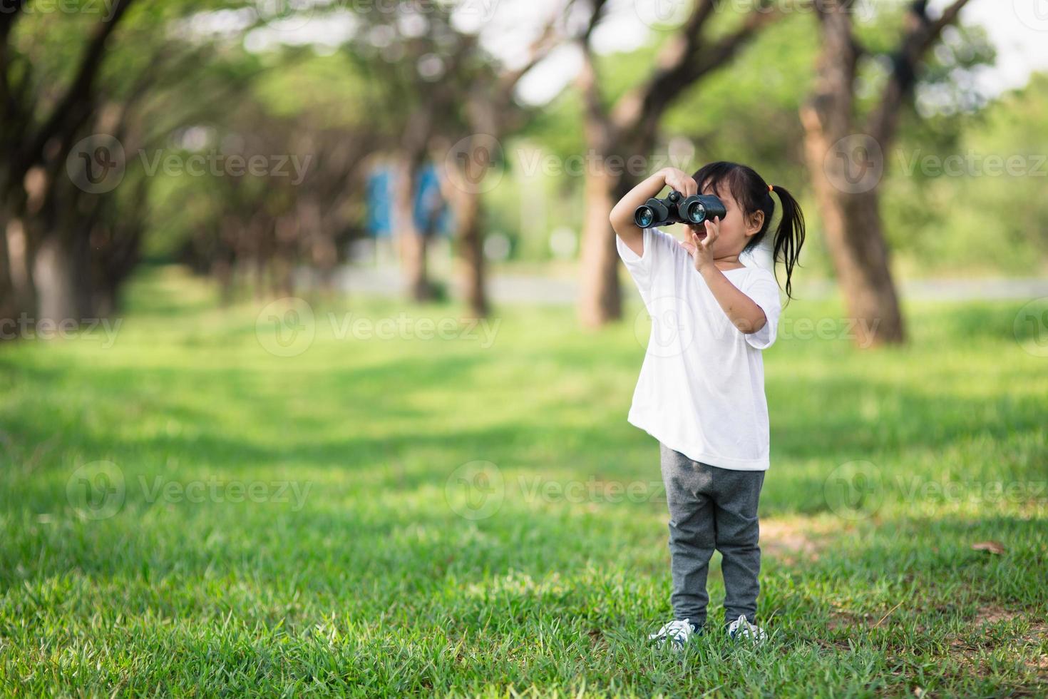 Happy child girl playing with binoculars. explore and adventure concept photo