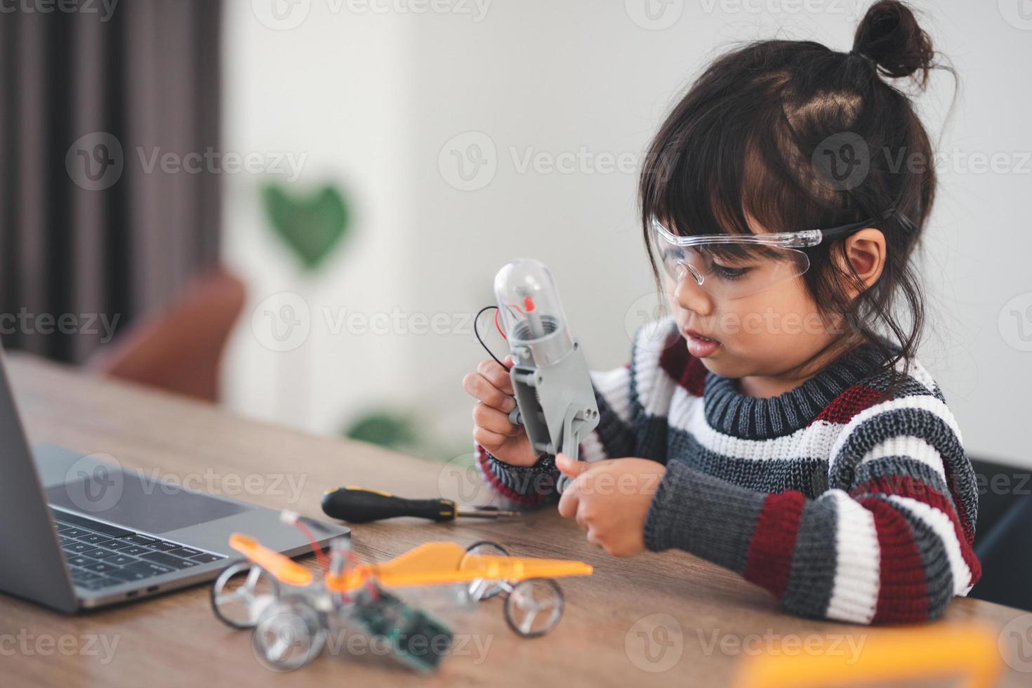Inventive kid constructing robot cars at home photo