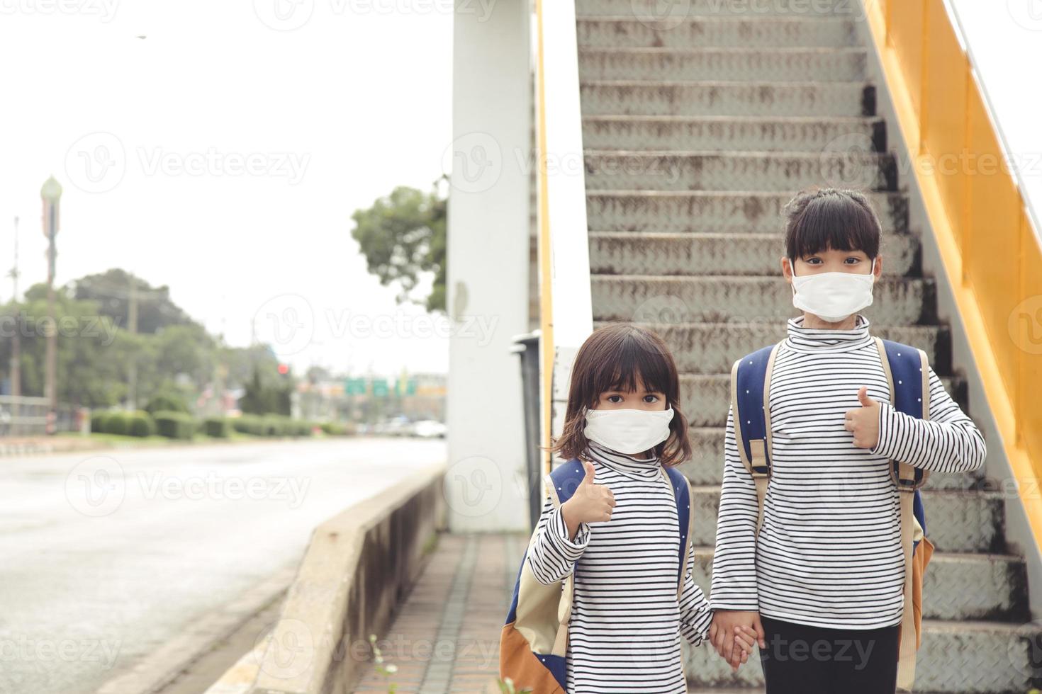 School child wearing a face mask during coronavirus and flu outbreak. Little girl going back to school after covid-19 quarantine and lockdown. photo