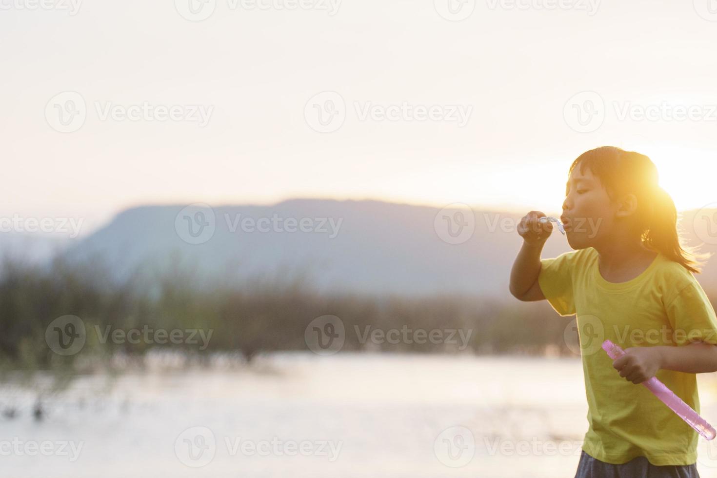Two happy little girls running around playing with soap bubbles in the backyard. Active healthy young children playing and making bubbles in the garden outside, family fun and siblings togetherness photo