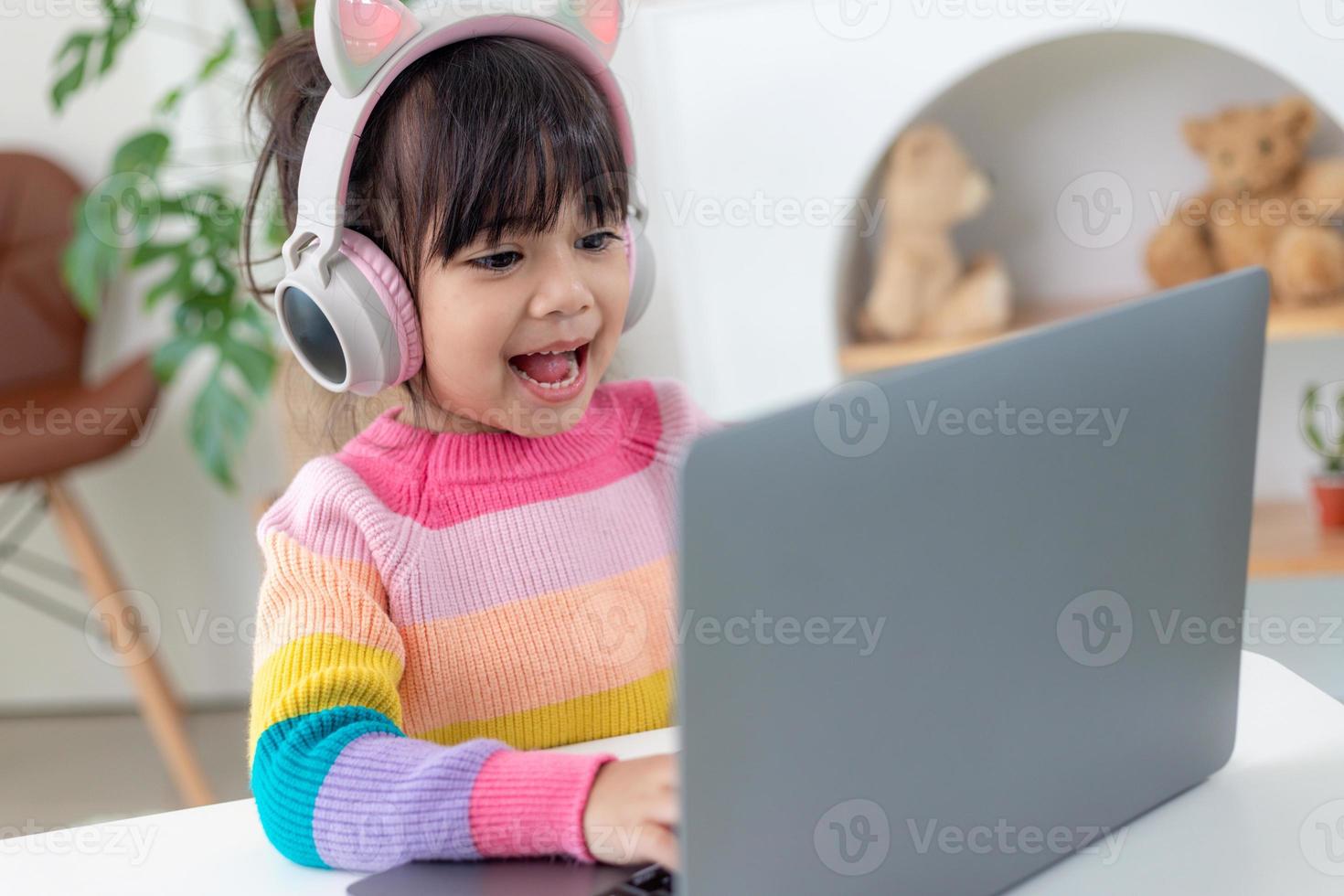 Smiling little Asian girl have a video call distant class with teacher using laptop, social distance during quarantine isolation during the Coronavirus photo