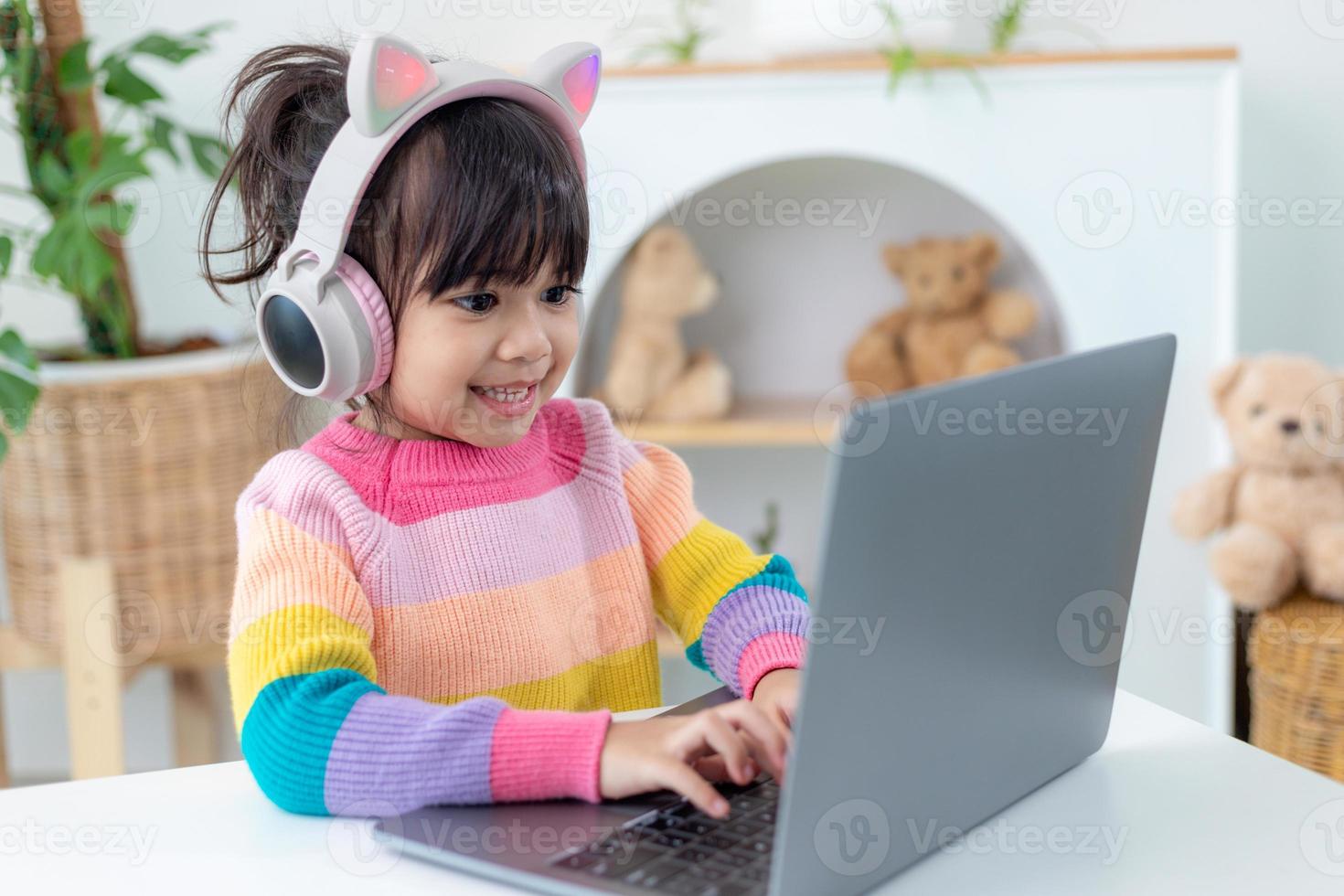 Smiling little Asian girl have a video call distant class with teacher using laptop, social distance during quarantine isolation during the Coronavirus photo