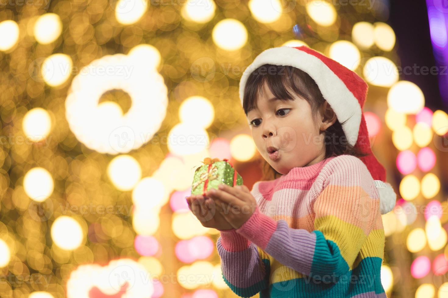 Happy child in Santa red hat holding Christmas presents. Christmas time. photo