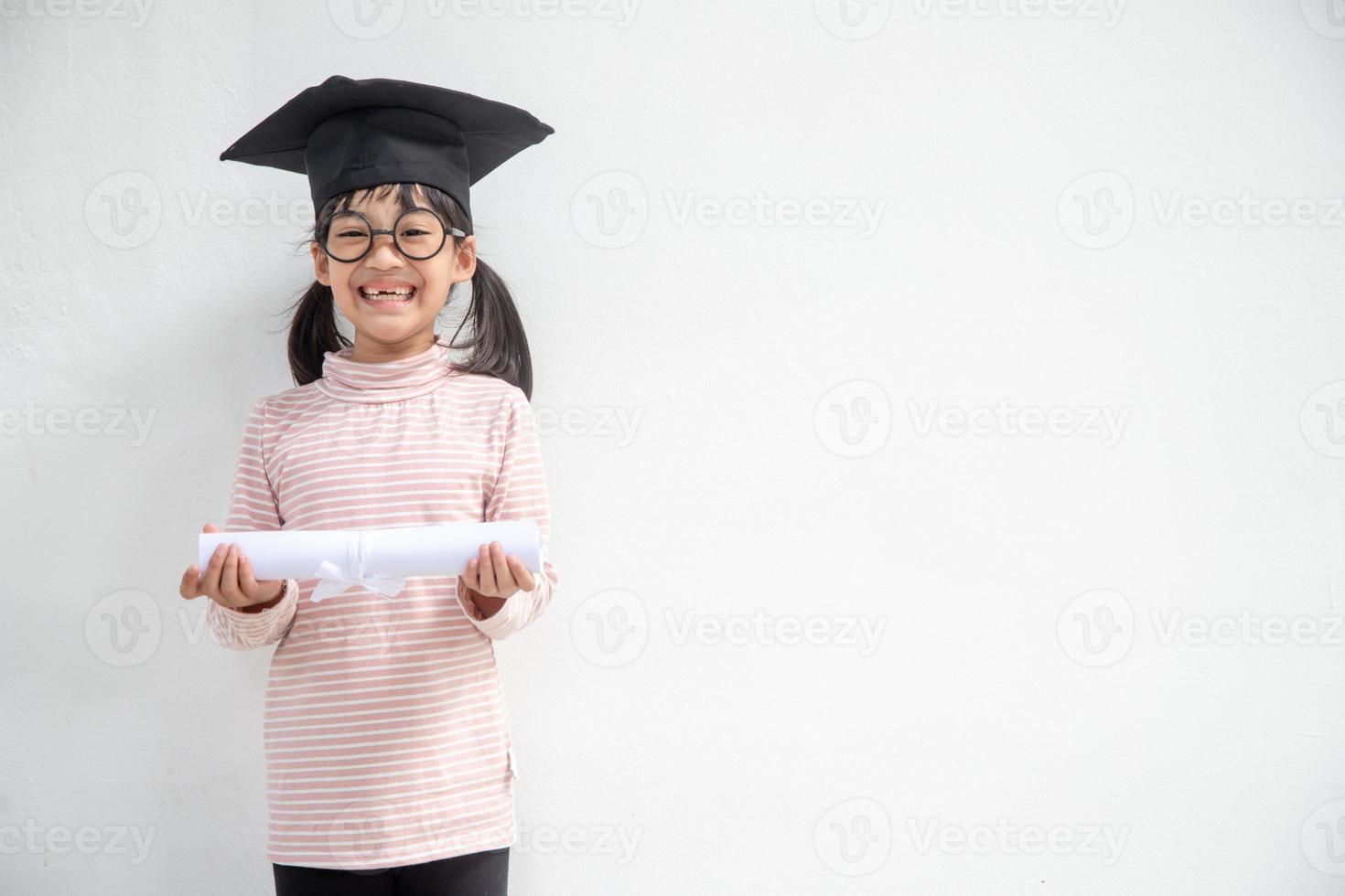 Happy Asian school kid graduate in graduation cap photo