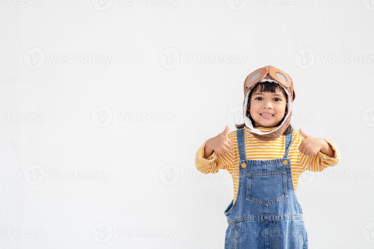 dreams of flight little child girl playing with a pilot hat on white background photo