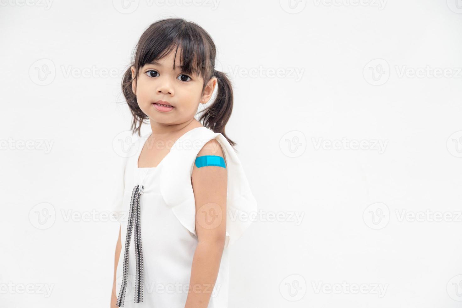 Asian little girl showing his arm after got vaccinated or inoculation, child immunization, covid delta vaccine concept photo