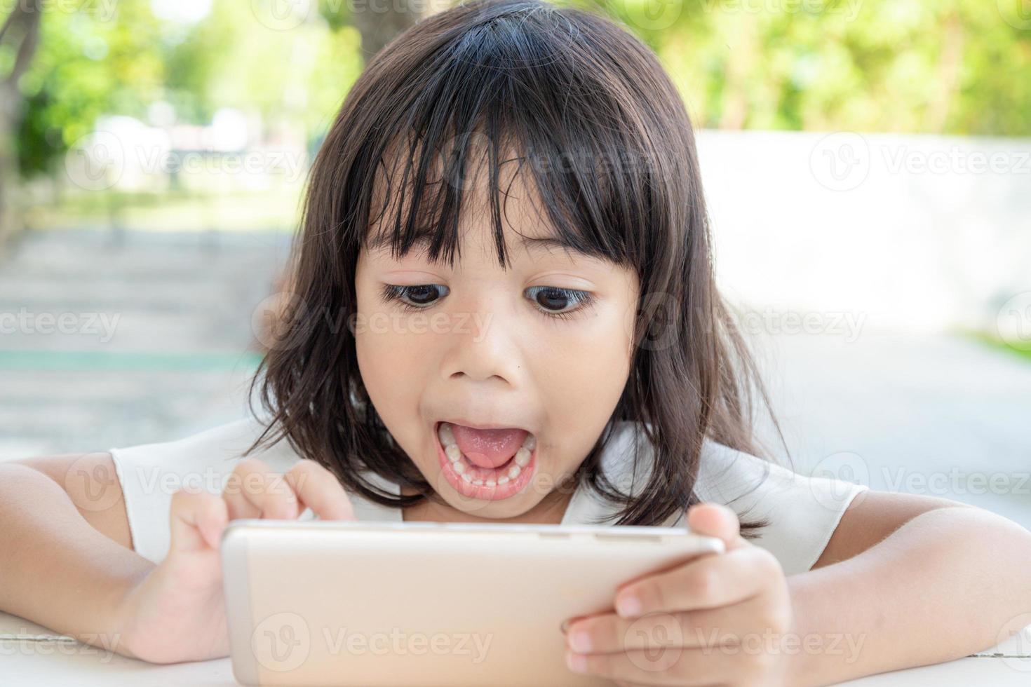 Shocked and surprised little girl on the internet with digital tablet computer concept for amazement, astonishment, making a mistake, stunned and speechless or seeing something he should not see photo