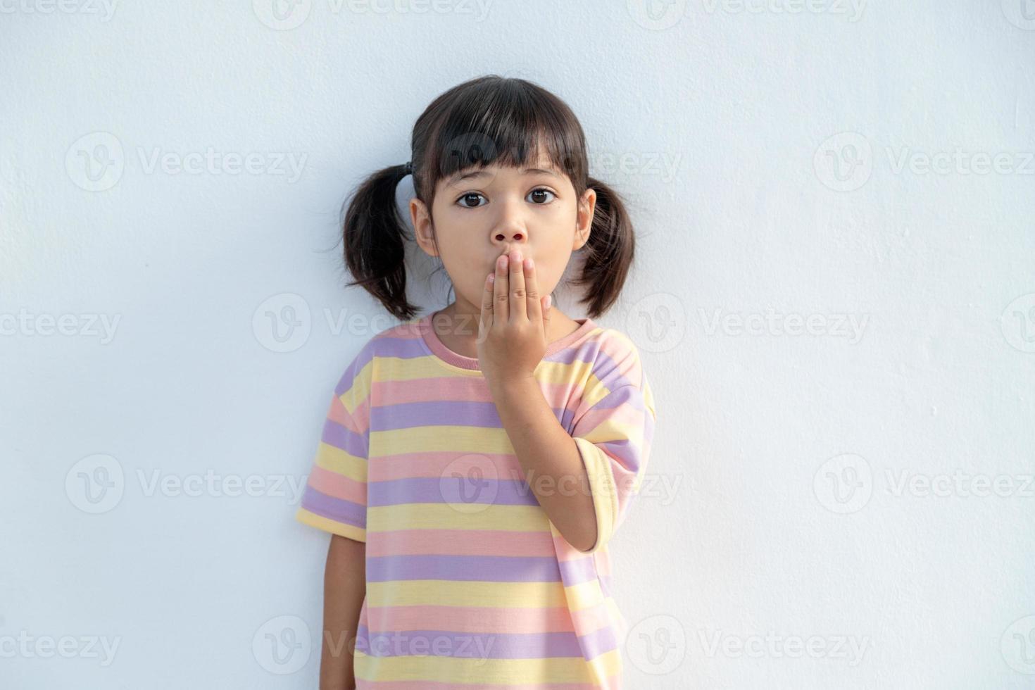 Portrait of surprised cute little toddler girl child standing isolated over white background. Looking at the camera. hands near open mouth photo