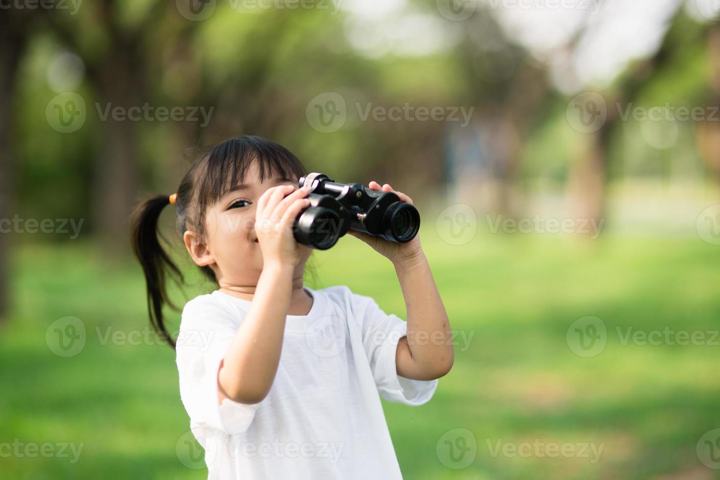 Happy child girl playing with binoculars. explore and adventure concept photo