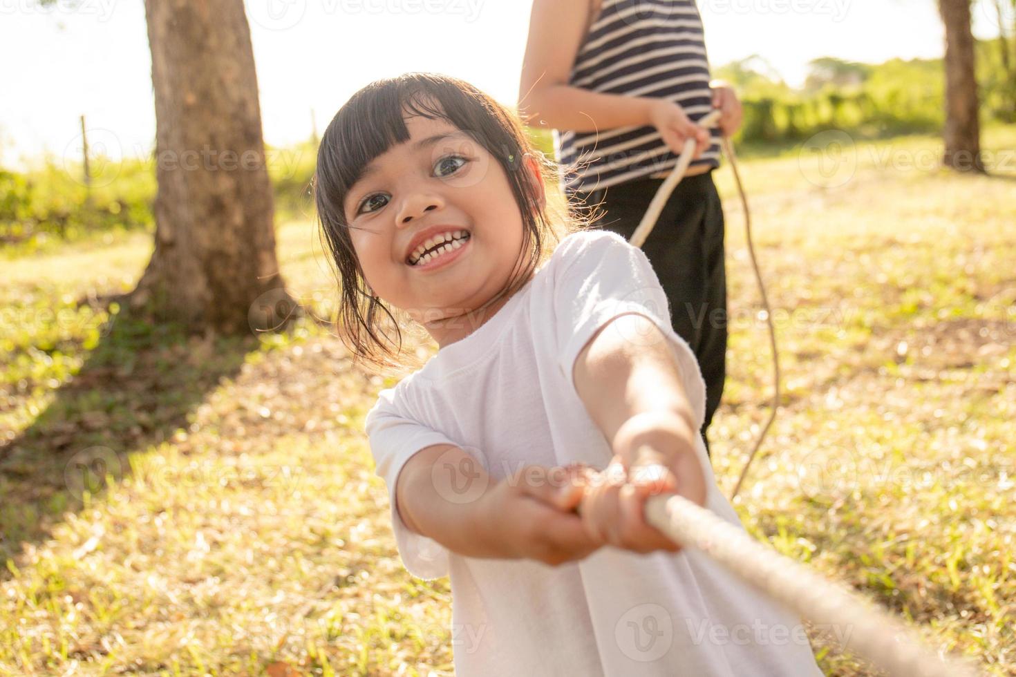 Children playing tug of war at the park on sunsut photo