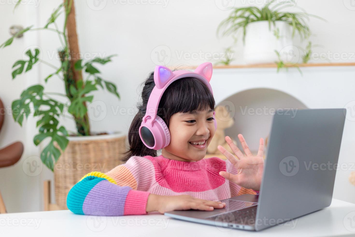 Smiling little Asian girl have a video call distant class with teacher using laptop, social distance during quarantine isolation during the Coronavirus photo