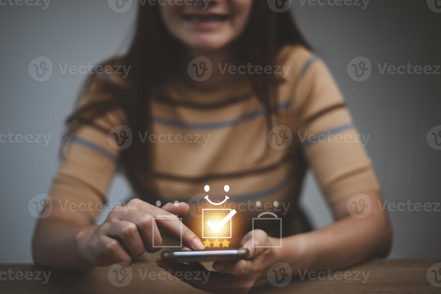 Customer satisfaction concept. female hand holding smartphone Show rating with five stars gold symbol and Smiley Face for her Satisfaction. photo