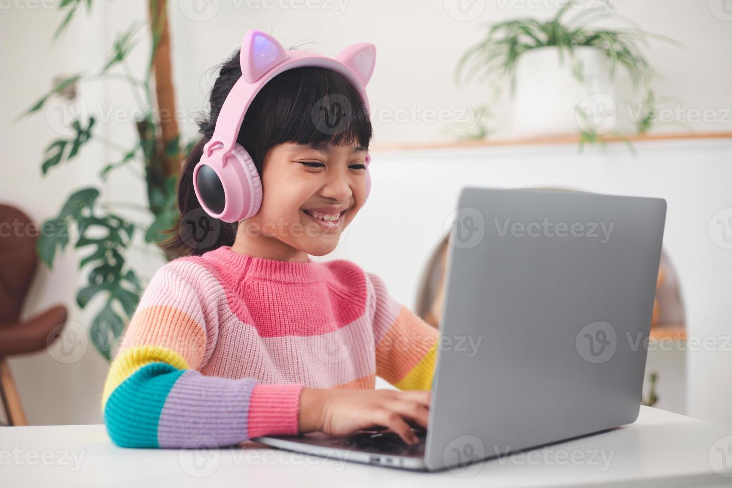 Smiling little Asian girl have a video call distant class with teacher using laptop, social distance during quarantine isolation during the Coronavirus photo