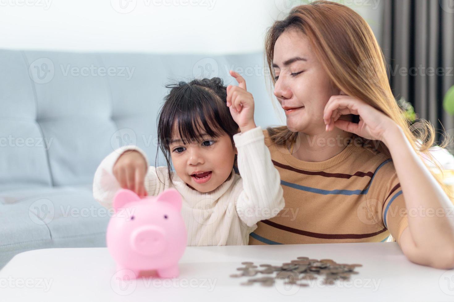 Mother and daughter putting coins into piggy bank. Family budget and savings concept. Junior Savings Account concept photo