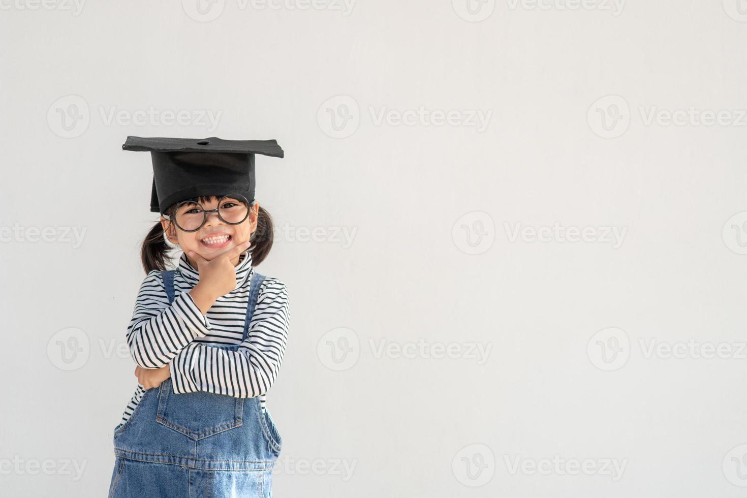 Happy Asian school kid graduate thinking with graduation cap photo