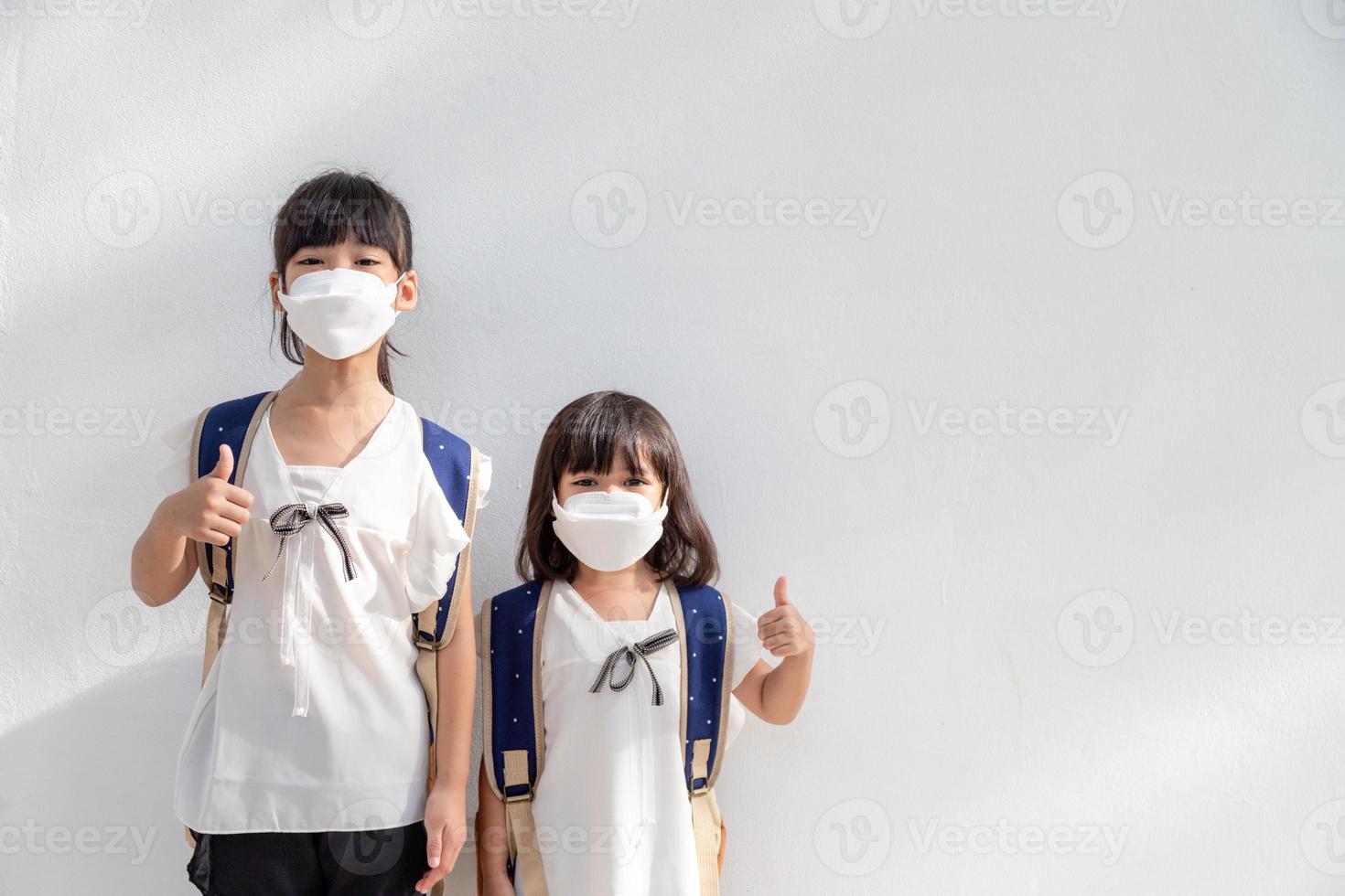 Sibling little girl wearing a mask to stop coronavirus outbreak.quarantine Asian sibling.covid-19 coronavirus and pandemic virus symptoms. photo