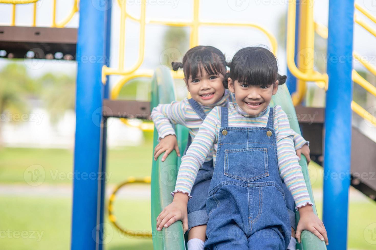 Cute little girls siblings having fun on playground outdoors on a sunny summer day. active sport leisure for kids photo