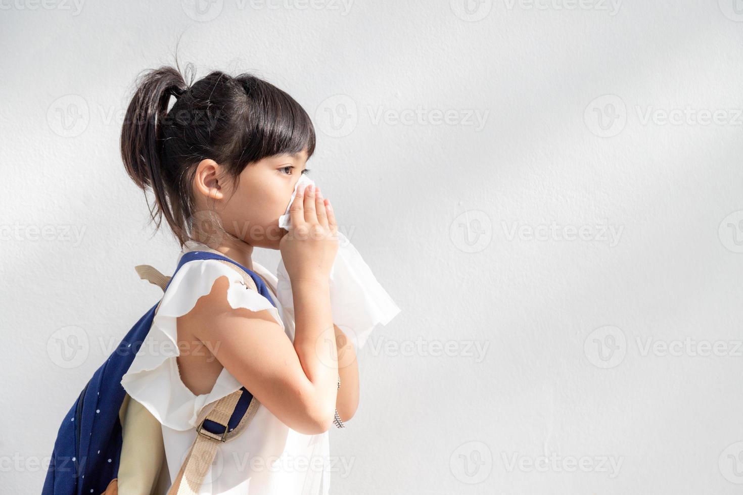 Asian child girl sick with sneezing on the nose and cold cough on tissue paper because weak or virus and bacteria from dust weather photo