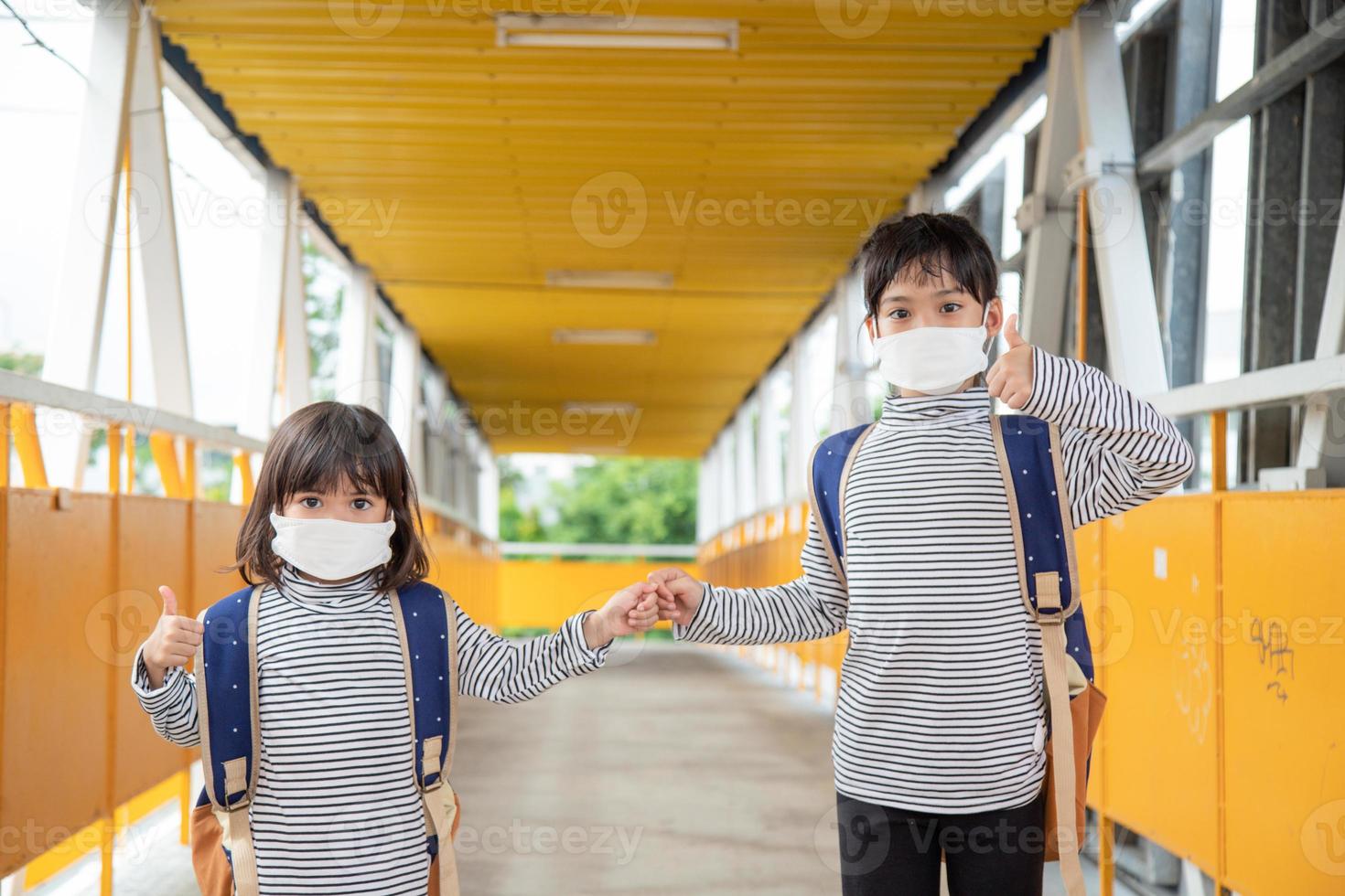 School child wearing a face mask during coronavirus and flu outbreak. Little girl going back to school after covid-19 quarantine and lockdown. photo
