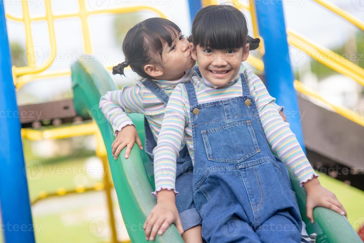 Cute little girls siblings having fun on playground outdoors on a sunny summer day. active sport leisure for kids photo