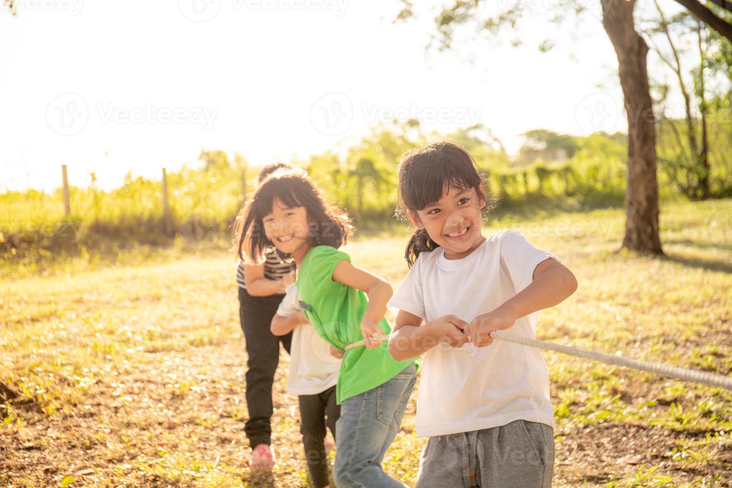 Children playing tug of war at the park on sunsut photo