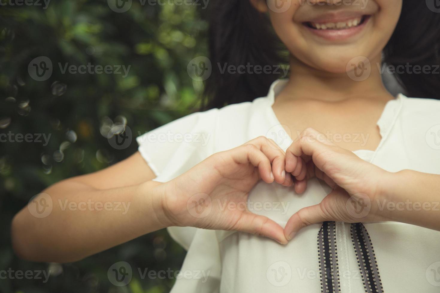 Little girl hands making a heart shape on white background photo