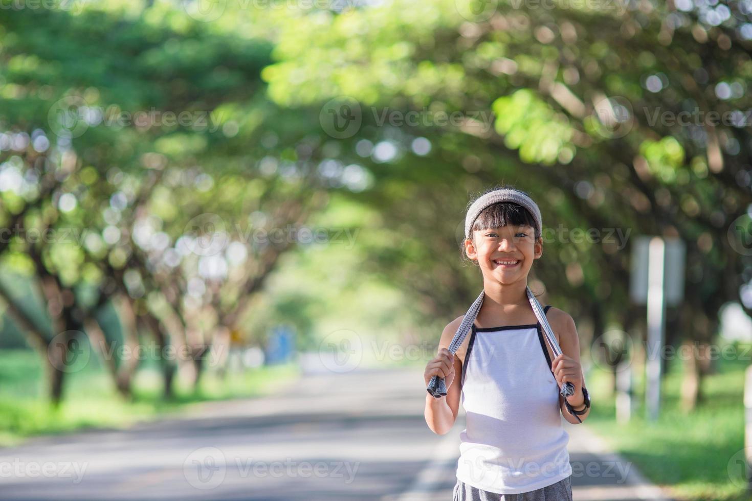 happy child girl running in the park in summer in nature. warm sunlight flare. asian little is running in a park. outdoor sports and fitness, exercise and competition learning for kid development. photo