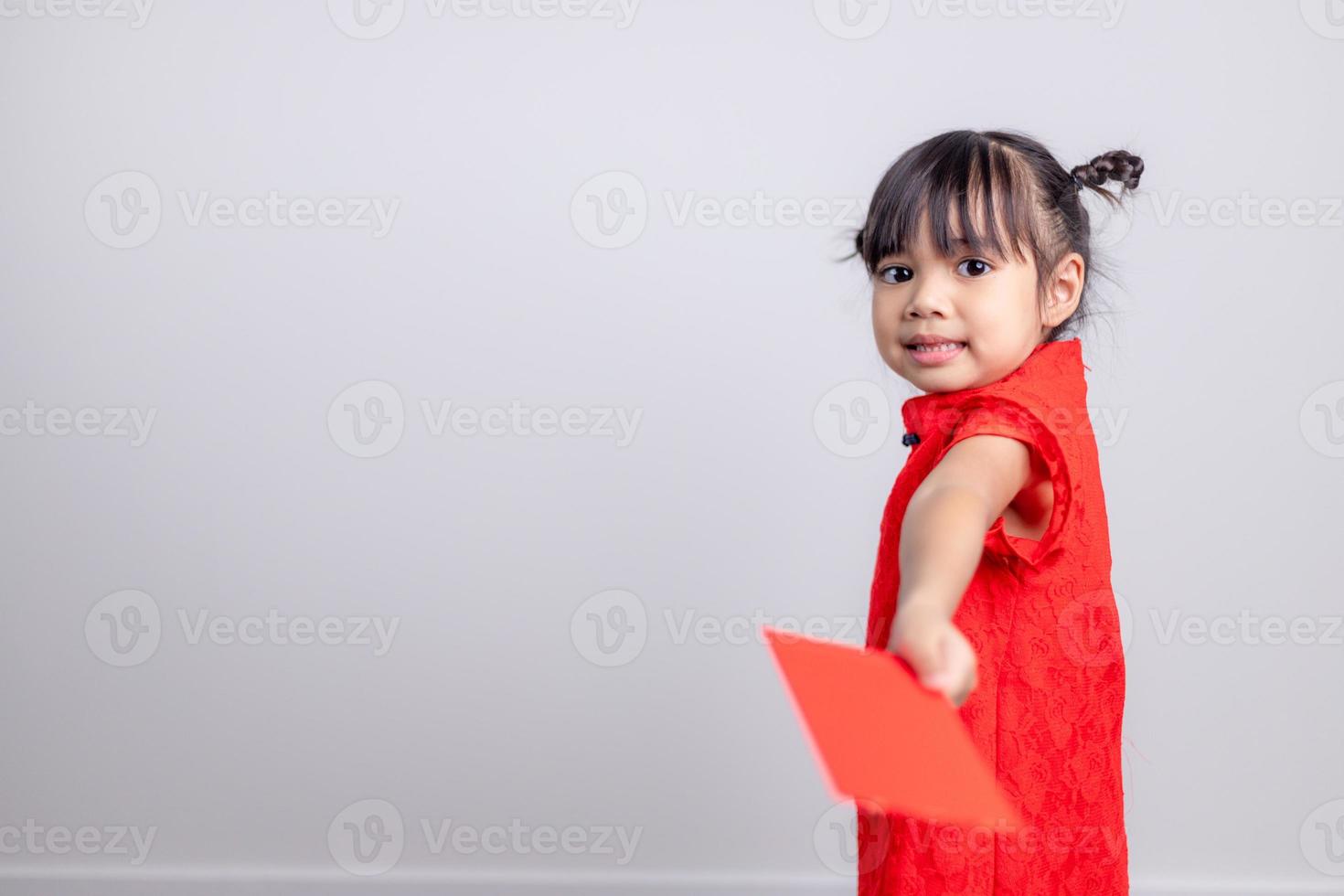 Happy Little Asian girl in Chinese traditional dress smiling and holding a red envelope. Happy Chinese new year concept. photo